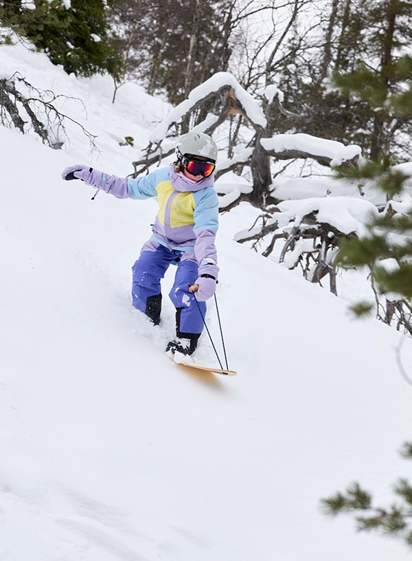 Copil coborând pe snowboard.