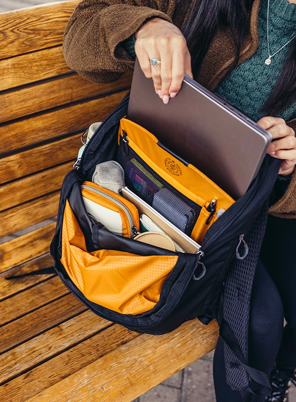 Femeie care bagă laptopul în rucsac.