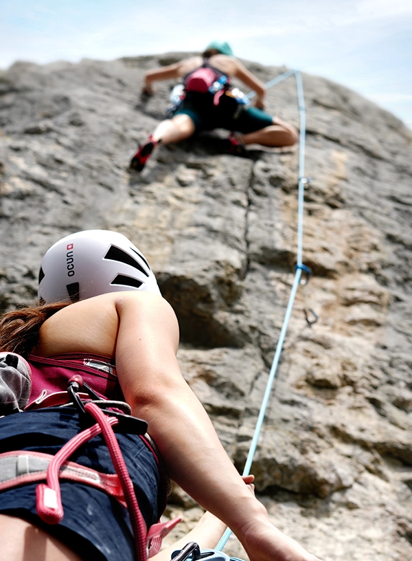 Doi cățărători în timpul parcurgerii unui traseu de escaladă.