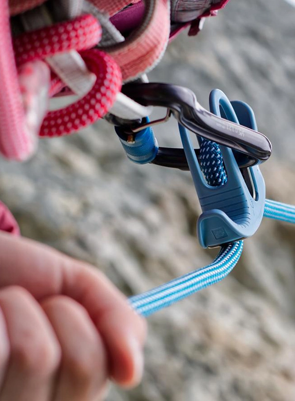 Vedere asupra dispozitivului prins în bucla de legătură a hamului în timpul asigurării cățărătorului.