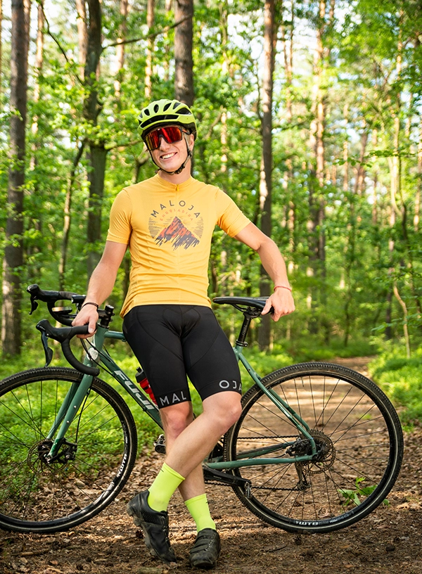 Ciclist stând pe o potecă în pădure, sprijinit de bicicletă