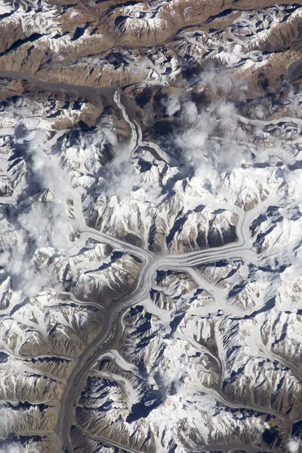 Cele mai înalte vârfuri din Karakorum într-o singură fotografie. În stânga, vârful K2 ieșind deasupra norilor, pe cealaltă parte a ghețarului Broad Peak, iar mai departe „potcoava” masivului Gasherbrumilor.